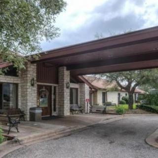 A driveway leading to a covered entrance of a residential building, surrounded by trees.