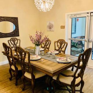 An elegantly set dining room with a wooden table, matching chairs, and a decorative chandelier overhead.