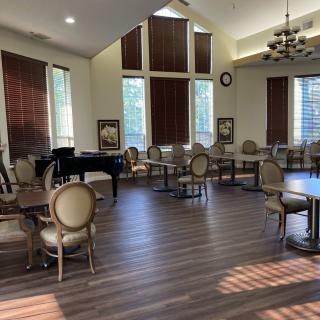 Sunlit room with a grand piano, chairs, and tables.