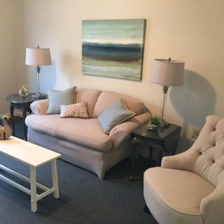 A cozy living room featuring a soft pink sofa and armchair, complemented by stylish lamps and abstract wall art.
