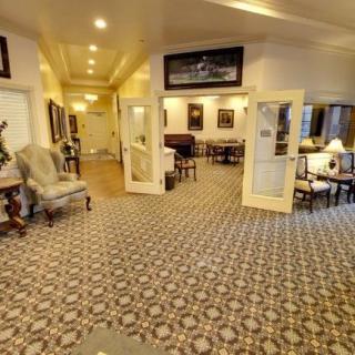 A well-decorated lobby with chairs, tables, and patterned carpeting.