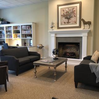 A cozy living room with sofas, a coffee table, bookshelf, and a fireplace.