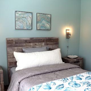 A serene and minimalistic bedroom featuring soft blue walls and rustic wooden furniture.