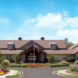 A beautifully landscaped clubhouse with a flag at the entrance under a clear blue sky.