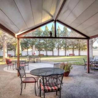 A covered patio area with metal furniture overlooking a garden.