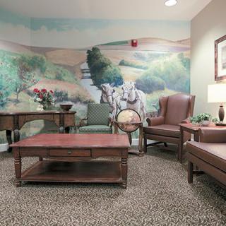 A cozy lobby area with comfortable seating and a countryside mural on the wall.