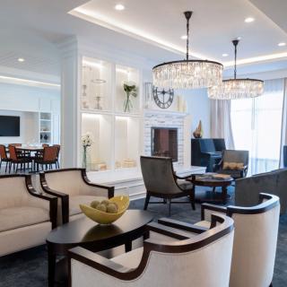 A modern living room with elegant chandeliers, comfortable seating, and a cozy fireplace.