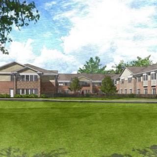 A scenic view of residential buildings with a green lawn and blue sky.
