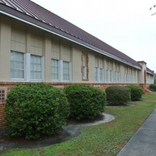 Exterior view of a building with bushes and a lawn.