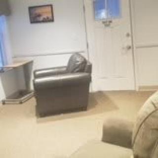 A cozy living room featuring a leather armchair, a small side table, and a carpeted floor.