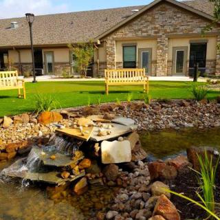 A landscaped garden with a pond and fountain in front of a building.