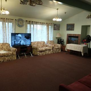 A cozy living room with patterned sofas, a television, and ample lighting.