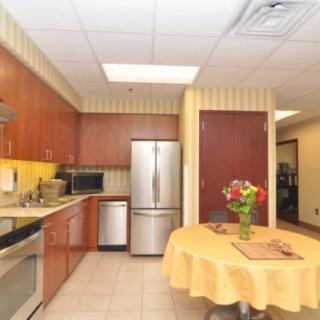A modern kitchen with wood cabinets and stainless steel appliances, featuring a table adorned with a floral arrangement.