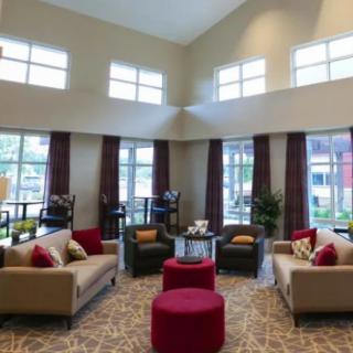A well-lit modern living room with comfortable seating and large windows.