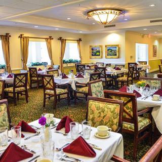 An elegant dining room with beautifully set tables, featuring floral arrangements and decorative elements.