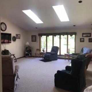 A spacious living room filled with natural light, featuring comfortable seating and a cozy atmosphere.