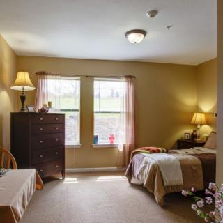 A cozy bedroom with a single bed, dresser, and lamps by the windows.