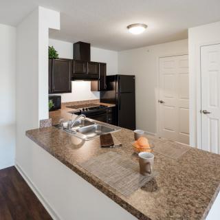 A modern kitchen with dark cabinets and a granite countertop.