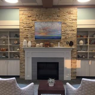 A cozy living room featuring a stone fireplace surrounded by built-in shelves filled with decorative items, and a seating area facing the fireplace.