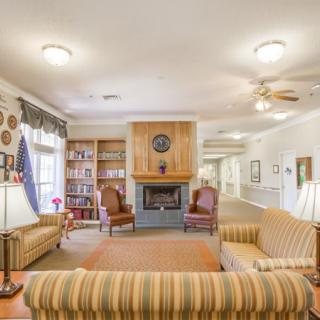 A cozy living room with a fireplace, striped sofas, and bookshelves lining the walls.