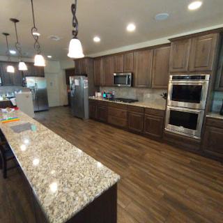 A spacious modern kitchen featuring granite countertops, wood cabinets, and stainless steel appliances.