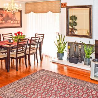 A cozy dining room with elegant decor, featuring a wooden table and chairs, plants by the fireplace, and a chandelier hanging above.