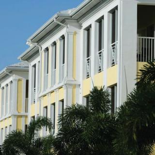 A tropical residential building with balconies and palm trees.
