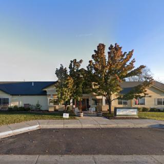 A suburban building with trees in front, viewed from the street on a sunny day.