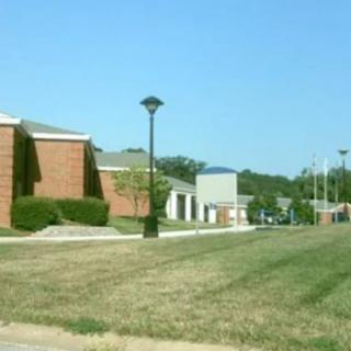 A row of buildings with a well-maintained lawn and pathway, featuring streetlights and trees under a clear blue sky.