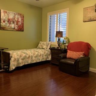 A cozy bedroom featuring a single bed, armchair, and decorative wall art.