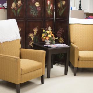 A cozy seating area featuring two yellow upholstered chairs and a small table with a flower arrangement.
