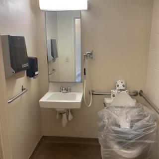 A clean and accessible bathroom featuring a sink, mirror, hand dryer, and toilet.