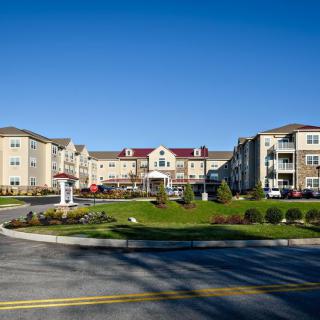 A modern apartment complex with landscaped grounds under a clear blue sky.