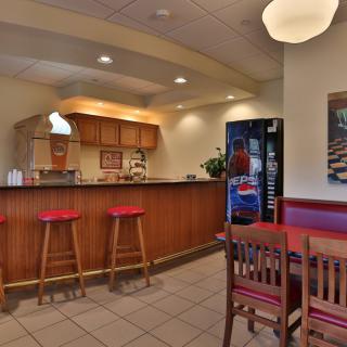 A cozy cafe interior with a counter, bar stools, and a seating area.