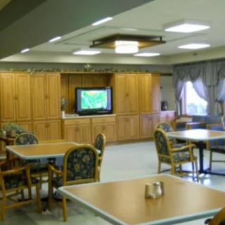 A cozy dining area with wooden tables and chairs, featuring a television in the background.
