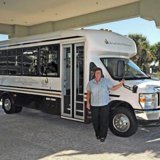 A person standing next to a white bus in an outdoor setting.