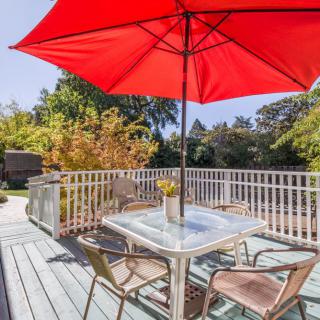 A sunny patio with a table, chairs, and a bright red umbrella.