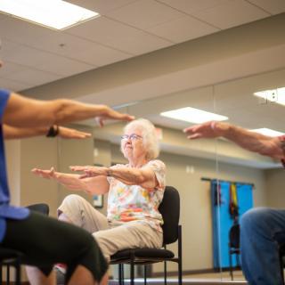 A group of seniors participating in a seated exercise class.
