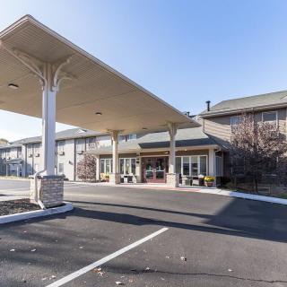 A commercial building with a large canopy covering the entrance and an adjacent parking lot.