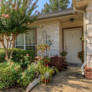 A charming house entrance surrounded by a lush garden and various plants.