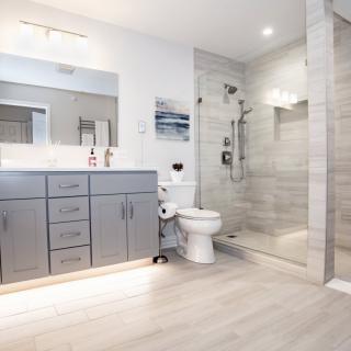 A modern, spacious bathroom with a gray vanity, glass shower enclosure, and minimalist design.