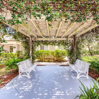 A tranquil garden pergola with benches, adorned with lush greenery and vines.