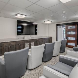 A modern conference room with comfortable seating and a large television.
