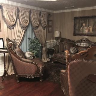 A traditionally decorated living room with ornate furniture and draped curtains.