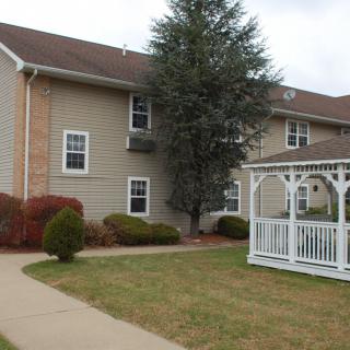 A residential building with a white gazebo and surrounding lawn area.