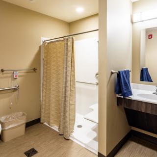 A clean and modern bathroom featuring a shower area, sink, and neatly hung towels.