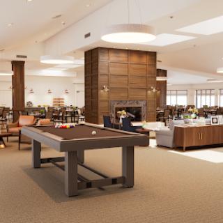 A spacious and modern lounge area featuring a billiards table, comfortable seating, and a warm fireplace, perfect for relaxation and social gatherings.