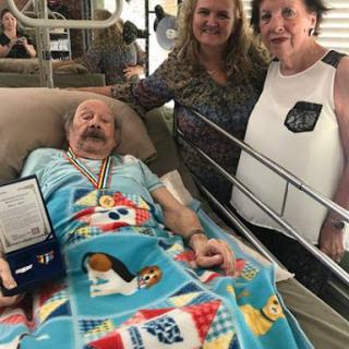 A heartwarming moment in a hospital room, where family members gather around a patient adorned with medals.