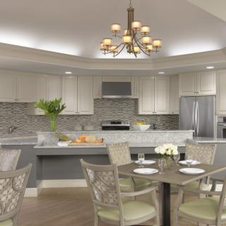 A modern kitchen with a dining area featuring a chandelier, marble countertops, and stainless steel appliances.