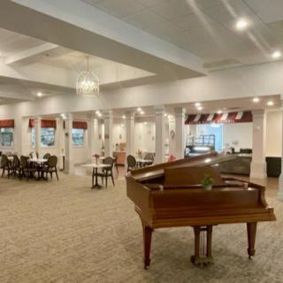 A spacious dining area featuring a grand piano and elegant decor.